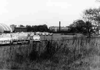 Parkeringen vid skolan i kv Storken mot öster. Baraccudatältet, tingsrätten, sporthallen ca 1974